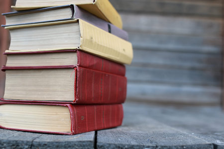 books standing different objects on a wooden table on a background of blurred summer foliageの写真素材