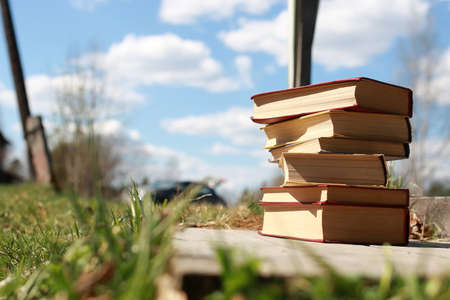 books standing different objects on a wooden table on a background of blurred summer foliageの写真素材