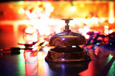 reception bell on the table and color shining garland on backgroundの写真素材