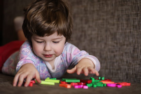 child playing with small toys on the couch in roomの写真素材