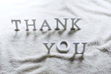 Wooden wthite letter Thank you on the crumpled carpet on the floorの写真素材