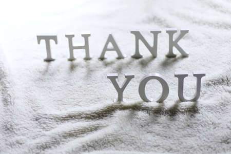 Wooden wthite letter Thank you on the crumpled carpet on the floorの写真素材