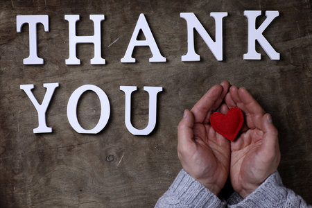 thank you word from white wooden letters on a table and hands
