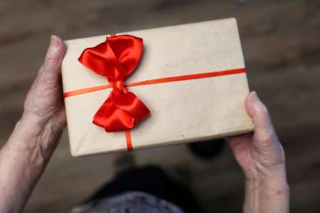 gift box with red bow in grandmother hands macroの写真素材