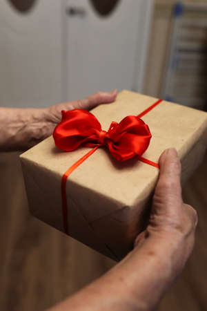 gift box with red bow in grandmother hands macroの写真素材