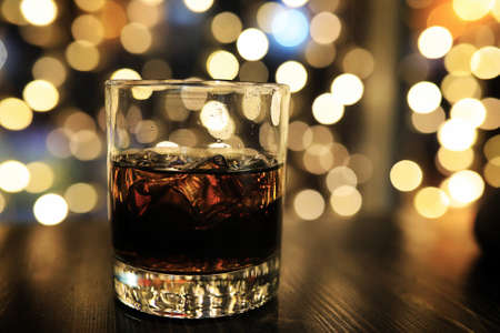 glass of alcohol with ice on blured background with circle bokehの写真素材