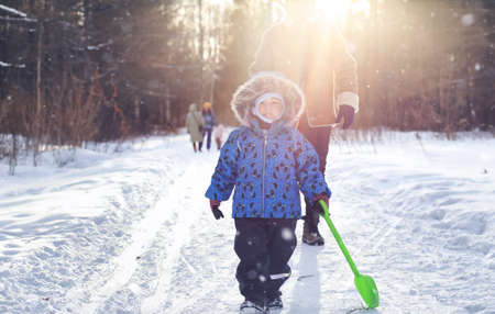 Kid playing in a winter park and have fun with familyの写真素材