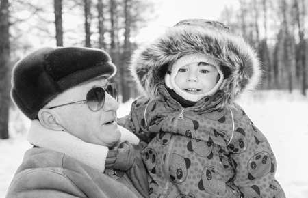 Black and white photo of parent holding kid on hands in winter pの写真素材