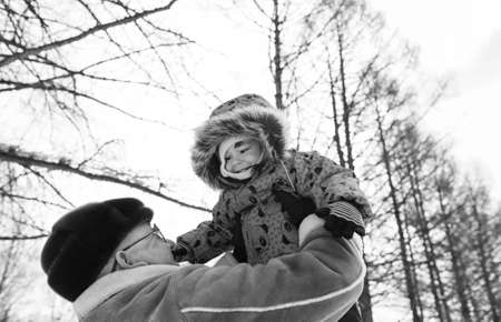Black and white photo of parent holding kid on hands in winter pの写真素材