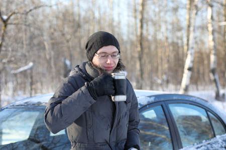 Man drink hot tea from mug outdoor in winter dayの写真素材
