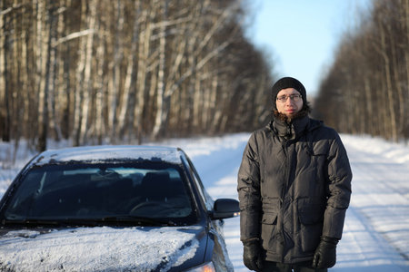 Winter rural road in forest in sunny day and man with carの写真素材
