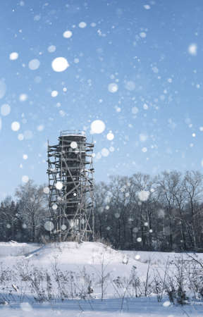 Scaffold around the water tower in field in front of forest in sの写真素材