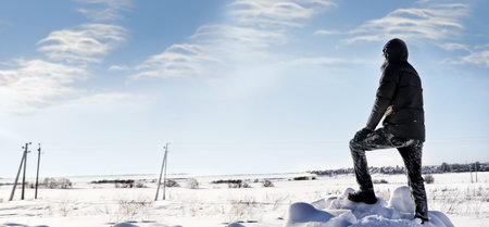 silhouette of man standing in winter field in sunny dayの写真素材