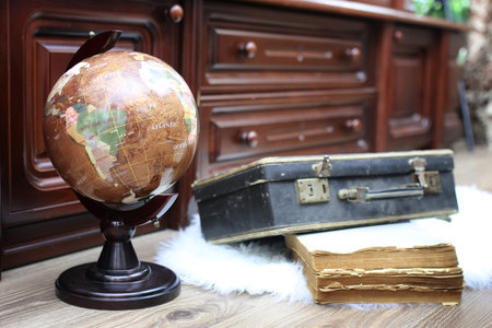 composition on a wooden floor vintage globe with old leather suiの写真素材