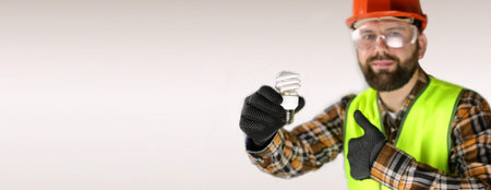 Worker in a helmet and protective clothing with a light bulb inの写真素材