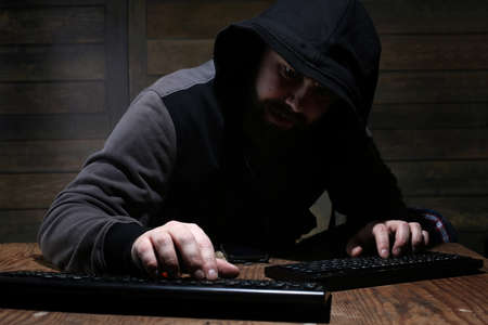hacker in the black hood in a room with wooden wallsの写真素材