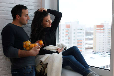 beautiful young couple looks into the distance through the windoの写真素材