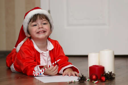 child in a suit of Santa Claus writing a letterの写真素材