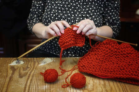 elderly woman is engaged in knitting warm sweaters for her grandの写真素材