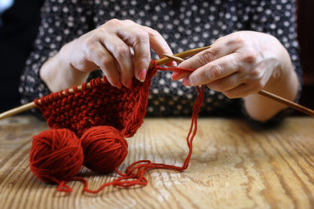 elderly woman is engaged in knitting warm sweaters for her grandの写真素材