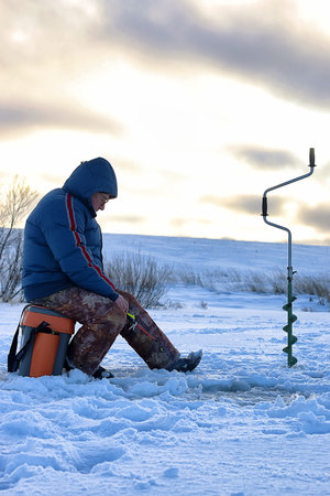 elderly man fishing in the winter on the lake