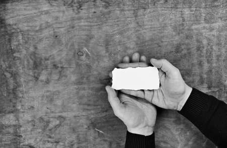 monochrome photo male hands holding a white blank sheet of paperの写真素材