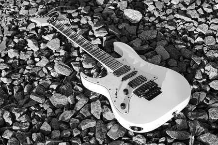 black and white electric guitar on the railroad tracks and stoneの写真素材