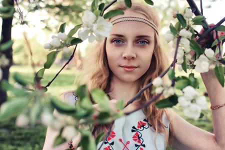 Girl in the spring walks through the apple alley in evening
