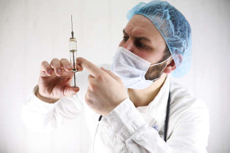 Crazy bearded doctor in a white coat and old syringeの写真素材