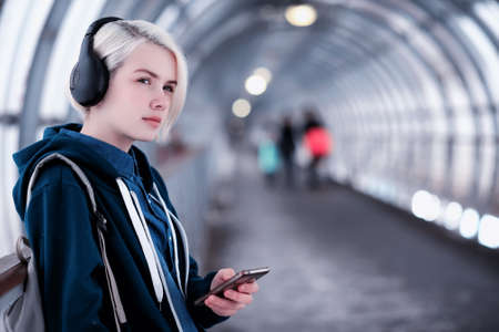 Young student listening to music in big headphones in the subwayの写真素材