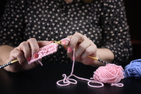 elderly woman is engaged in knitting warm sweaters for her grand