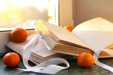 tangerines and vintage books on a marble table by the windowの写真素材