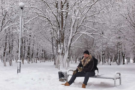 bearded man sitting in a winter parkの写真素材