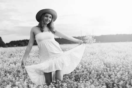 monochrome portrait of young girl in a hat standing in a huge fiの写真素材