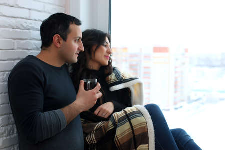 beautiful young couple looks into the distance through the windoの写真素材