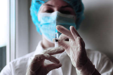 health worker dials the vaccine into a syringeの写真素材