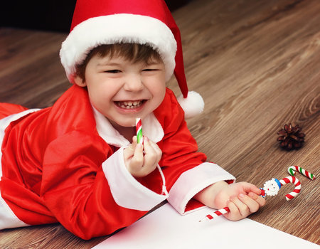 child in a suit of Santa Claus writing a letterの写真素材