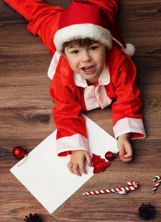 child in a suit of Santa Claus writing a letterの写真素材