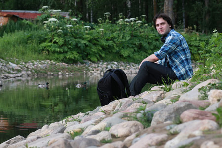 man sit on stone river