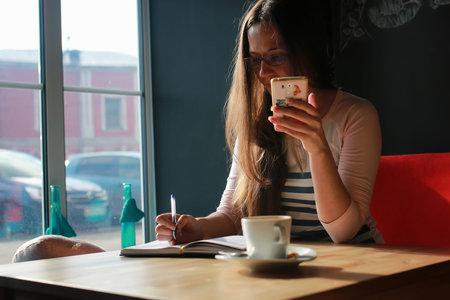 girl in a cafe for a cup of coffee with the notebookの写真素材