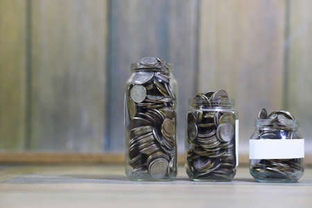 Accumulated coins stacked in glass jarsの写真素材