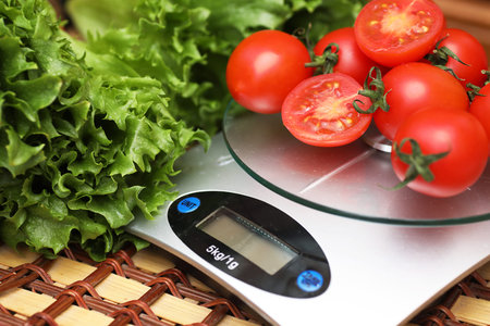 Fresh tomatoes on kitchen scales weighingの写真素材