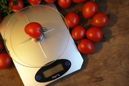 Fresh tomatoes on kitchen scales weighingの写真素材