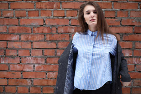 Young beautiful girl near red brick wall posingの写真素材
