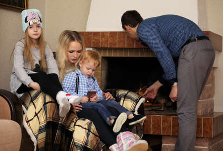 Family warmed by the fireplace sitting on the couchの写真素材