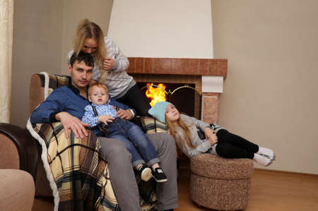family warmed by the fireplace sitting on the couchの写真素材