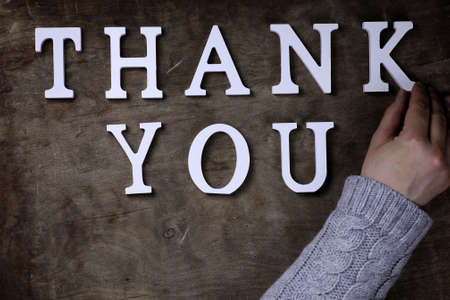 thank you word from white wooden letters on a table and handsの写真素材
