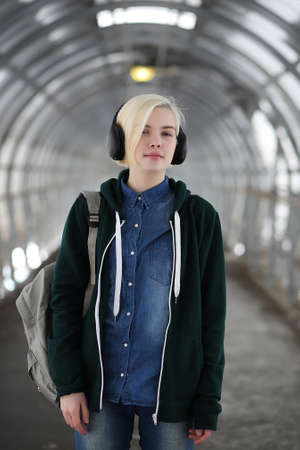 Young girl listens to music in big headphones in the subwayの写真素材