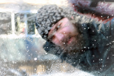 man cleans snow from the glass at the car