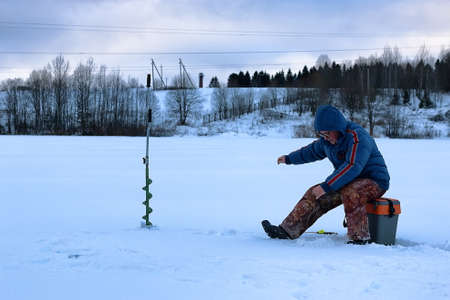 elderly man fishing in the winter on the lakeの写真素材